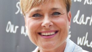 Close-up of a smiling woman with short blond hair and blue eyes.